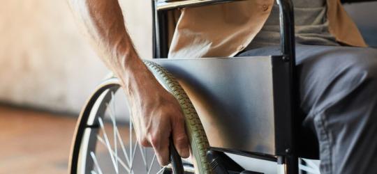 Mężczyzna porusza się na wózku, cierpi na stwardnienie zanikowe boczne.