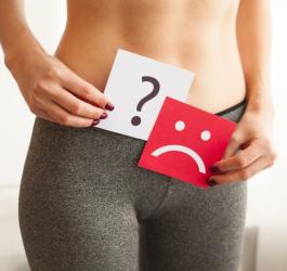 Kobieta trzyma kartkę ze smutną buźką, doskwiera jej suchość pochwy.