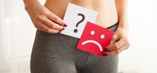 Kobieta trzyma kartkę ze smutną buźką, doskwiera jej suchość pochwy.