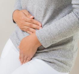 Kobieta trzyma się za okolicę miejsc intymnych.