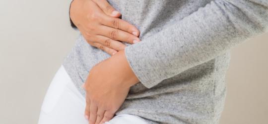 Kobieta trzyma się za okolicę miejsc intymnych.