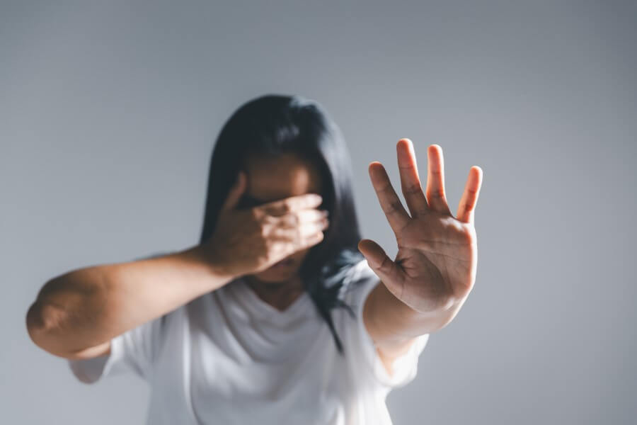 Kobieta zasłania się dłońmi przed światłem, cierpi na światłowstręt.