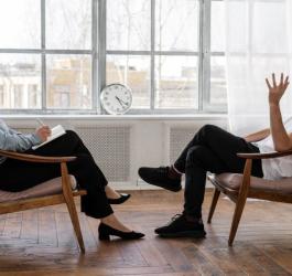 Mężczyzna podczas spotkania z terapeutką. Siedzą naprzeciwko siebie.