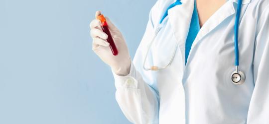 Lekarka trzyma w dłoni fiolkę z krwią pacjenta, przeznaczoną do testu OGGT czyli krzywej cukrowej.