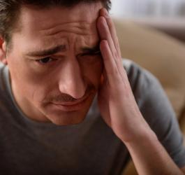 Mężczyzna zmaga się z silnym bólem głowy.