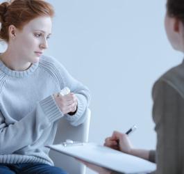 Zmartwiona kobieta podczas wizyty u terapeuty, z którym rozmawia m.in. o tokofobii.