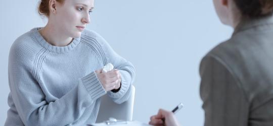 Zmartwiona kobieta podczas wizyty u terapeuty, z którym rozmawia m.in. o tokofobii.