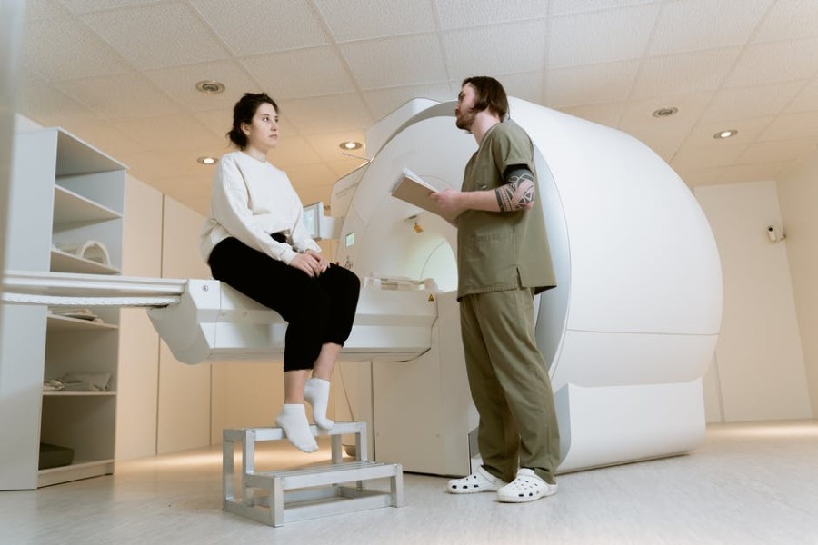 Technik tłumaczy pacjentce przebieg badania rezonansem magnetycznym.
