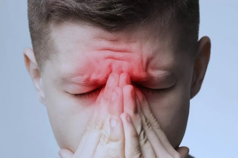Mężczyzna trzyma się za nasadę nosa.