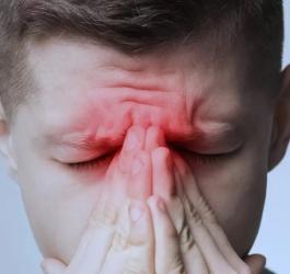 Mężczyzna trzyma się za nasadę nosa.