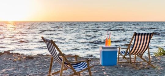 Leżaki plażowe i schłodzone napoje na tle nadmorskiego zachodu słońca.