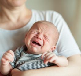 Zapłakany noworodek na rękach mamy.