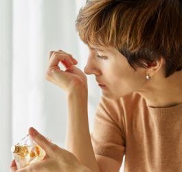 Kobieta próbuje poczuć zapach perfum na nadgarstku.