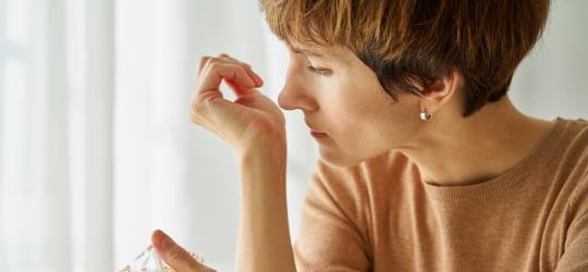 Kobieta próbuje poczuć zapach perfum na nadgarstku.