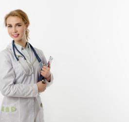 Młoda lekarka w kitlu i ze stetoskopem przewieszonym przez szyję. W ręce trzyma dokumenty.