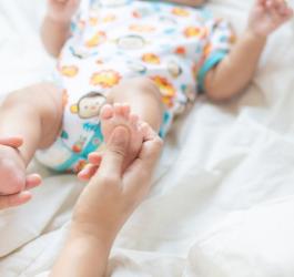 Rodzic trzyma niemowlę za stopy.
