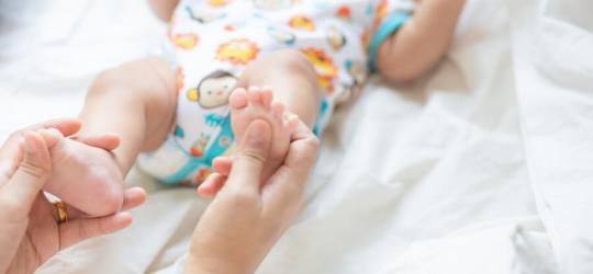 Rodzic trzyma niemowlę za stopy.