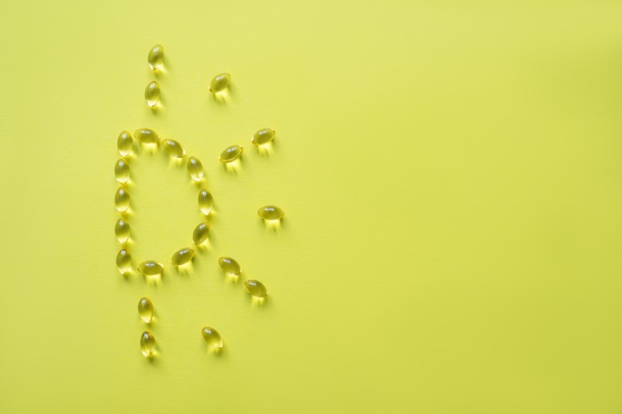 Żelowe kapsułki ułożone w słoneczną literę D, symbolizującą witaminę D.