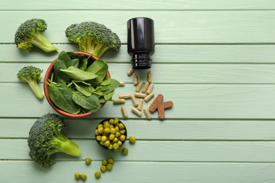 Suplement z witaminą K oraz warzywa zawierające tę witaminę.