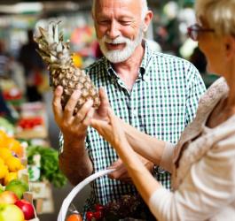 Małżeństwo seniorów wybiera owoce podczas zakupów spożywczych.