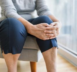 Starsza kobieta trzyma się za nogę, dokucza jej woda w kolanie.