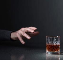 Dłoń sięgająca po szklankę z alkoholem.