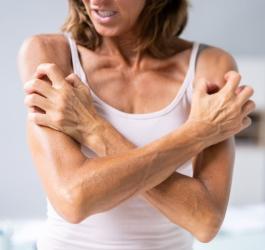 Kobieta ma na skórze wysypkę alergiczną, mocno drapie się po ramionach.