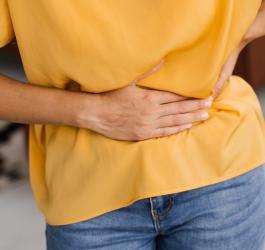 Kobieta trzyma się za brzuch, dokuczają jej wzdęcia.