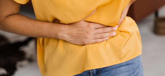 Kobieta trzyma się za brzuch, dokuczają jej wzdęcia.