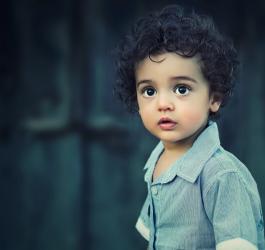 Zdjęcie dziecka o ciemnych, kręconych włosach.
