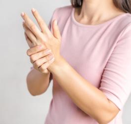 Kobieta trzyma się za jedną dłoń. Może cierpieć na zaburzenia czucia.