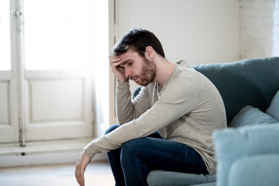 Zmartwiony z powodu zaburzeń erekcji mężczyzna siedzi na kanapie.