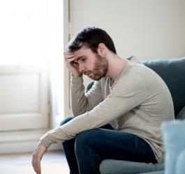 Zmartwiony z powodu zaburzeń erekcji mężczyzna siedzi na kanapie.