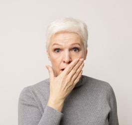 Kobieta z zaniepokojeniem spogląda w obiektyw, cierpi na zaburzenia mowy.