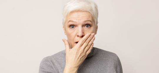 Kobieta z zaniepokojeniem spogląda w obiektyw, cierpi na zaburzenia mowy.