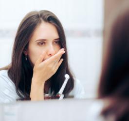 Kobieta przerywa szczotkowanie zębów z powodu bólu wywołanego zapaleniem dziąsła.