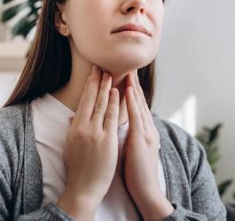 Dziewczyna dotyka swojej szyi, dokucza jej zapalenie gardła.