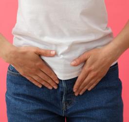 Kobieta trzyma się za okolicę podbrzusza, odczuwa ból w związku z infekcją.