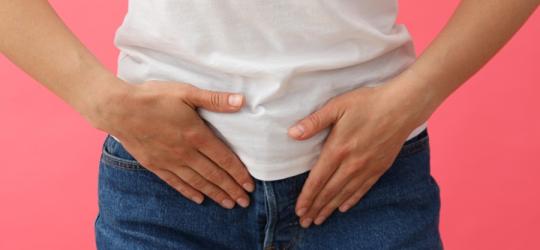 Kobieta trzyma się za okolicę podbrzusza, odczuwa ból w związku z infekcją.