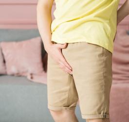 Mężczyzna trzyma się za krocze, doświadcza objawów zapalenia jądra.