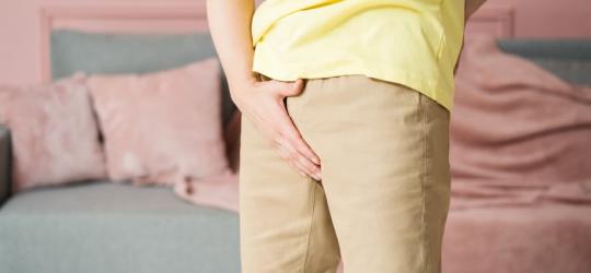 Mężczyzna trzyma się za krocze, doświadcza objawów zapalenia jądra.