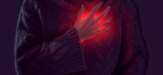 Kobieta trzyma się za klatkę piersiową, widoczny jest stan zapalny, sugerujący zapalenie osierdzia.