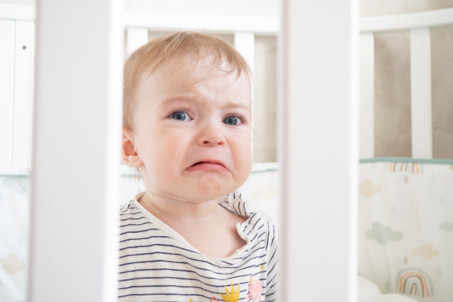 Płaczące niemowlę w łóżeczku.