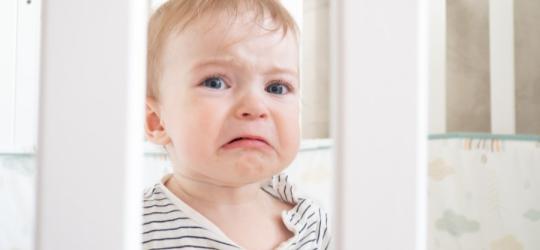 Płaczące niemowlę w łóżeczku.