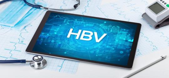 Tablet, obok sprzęt medyczny. Na tablecie napis HBV, skrót od wirusowego zapalenia wątroby typu B.