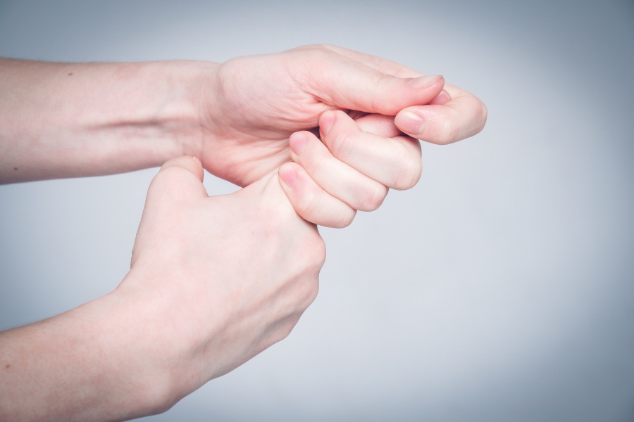 Kobieta trzyma się za palec wskazujący. Na palcu rozwinął się zastrzał.