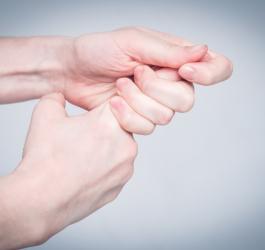 Kobieta trzyma się za palec wskazujący. Na palcu rozwinął się zastrzał.