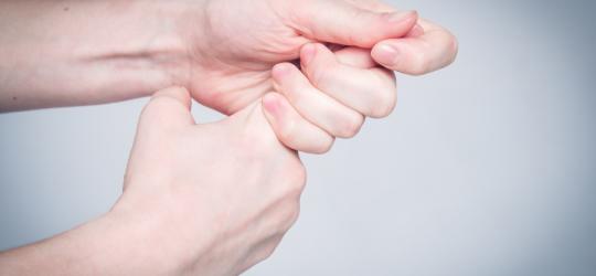 Kobieta trzyma się za palec wskazujący. Na palcu rozwinął się zastrzał.