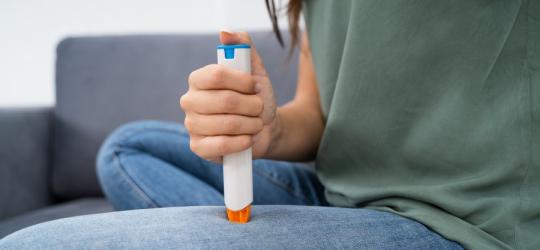 Kobieta wykonuje zastrzyk z adrenaliny przy pomocy pena.