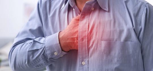 Mężczyzna chwyta się za klatę piersiową, cierpi na zespół Barlowa.